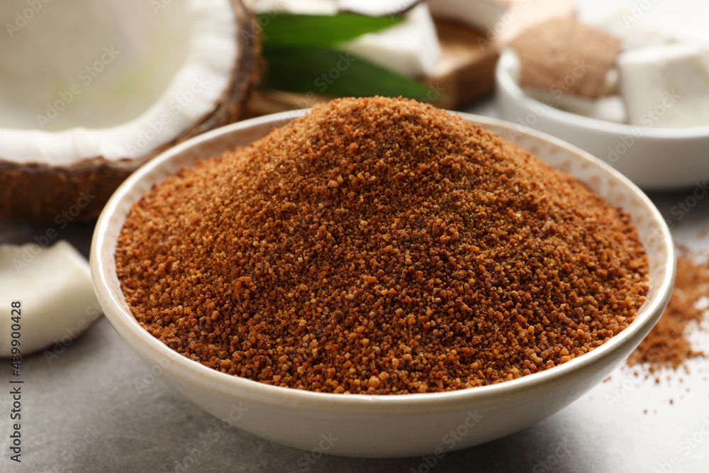 Natural coconut sugar in ceramic bowl on light grey table, closeup Natural coconut sugar in ceramic bowl on light grey table, closeup