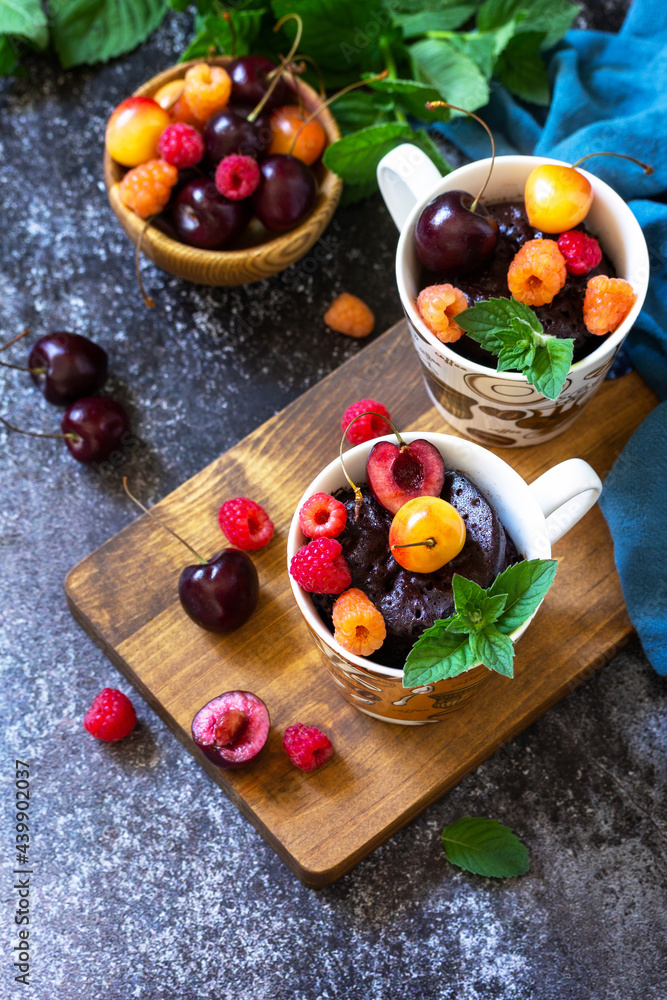 Summer breakfast or dessert. Chocolate cupcake in a mug is served with fresh summer berry raspberries and cherries. Copy space. Summer breakfast or dessert. Chocolate cupcake in a mug is served with fresh summer berry raspberries and cherries. Copy space.