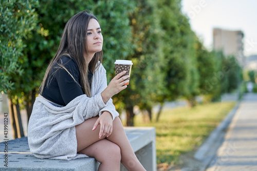 Young woman drinking coffee in a public park