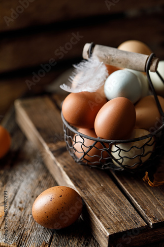 Chicken eggs with feathers in a basket on rustic background. Rustic style