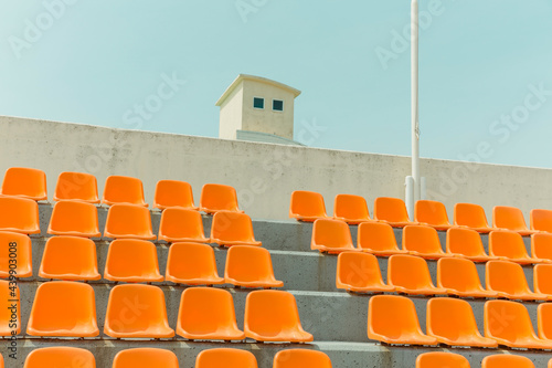The orange color bleachers are empty inside the stadium photo