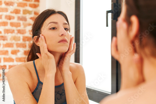 Young woman examining her complexion in a mirror