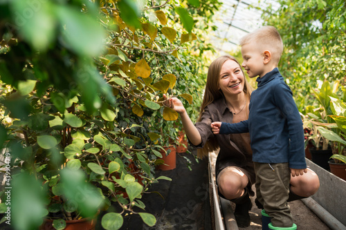 Mother shows her son plants in a greenhouse