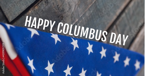 Happy columbus day text against folded american flag on wooden background