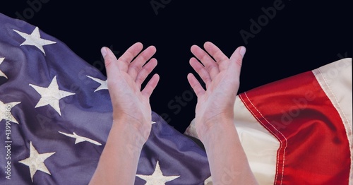 Composition of two hands welcoming above billowing american flag on black
