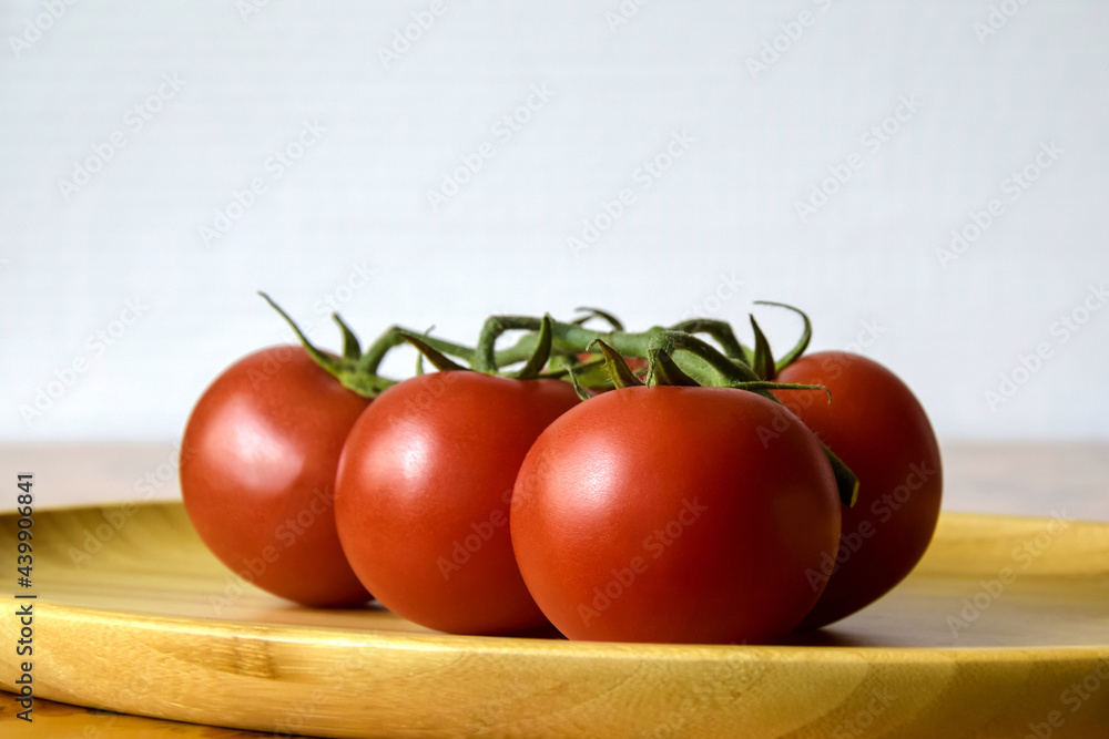 Ripe fresh tomato in wooden plate on kitchen table. Tasty red heirloom tomatoes. Close-up. Copy space. Ripe fresh tomato in wooden plate on kitchen table. Tasty red heirloom tomatoes. Close-up. Copy space.