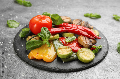 Delicious grilled vegetables with basil on grey table
