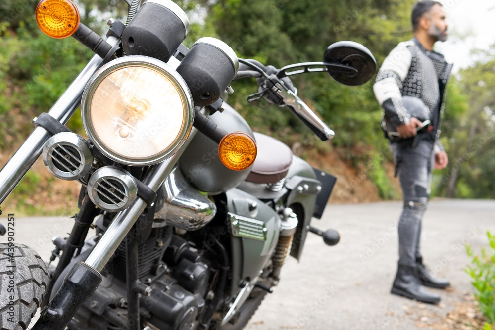 Man with helmet in hand standing near parked motorbike Man with helmet in hand standing near parked motorbike