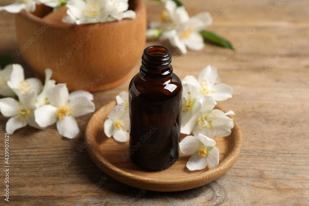 Jasmine essential oil and fresh flowers on wooden table Jasmine essential oil and fresh flowers on wooden table