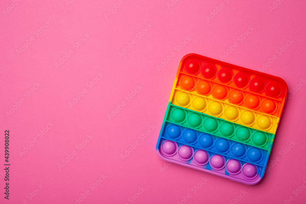 Simple dimple or pop it game on pink background with place for text. Top view of Push Pop Fidget Toy on color background. Silicon sensory anti stress toy Simple dimple or pop it game on pink background with place for text. Top view of Push Pop Fidget Toy on color background. Silicon sensory anti stress toy