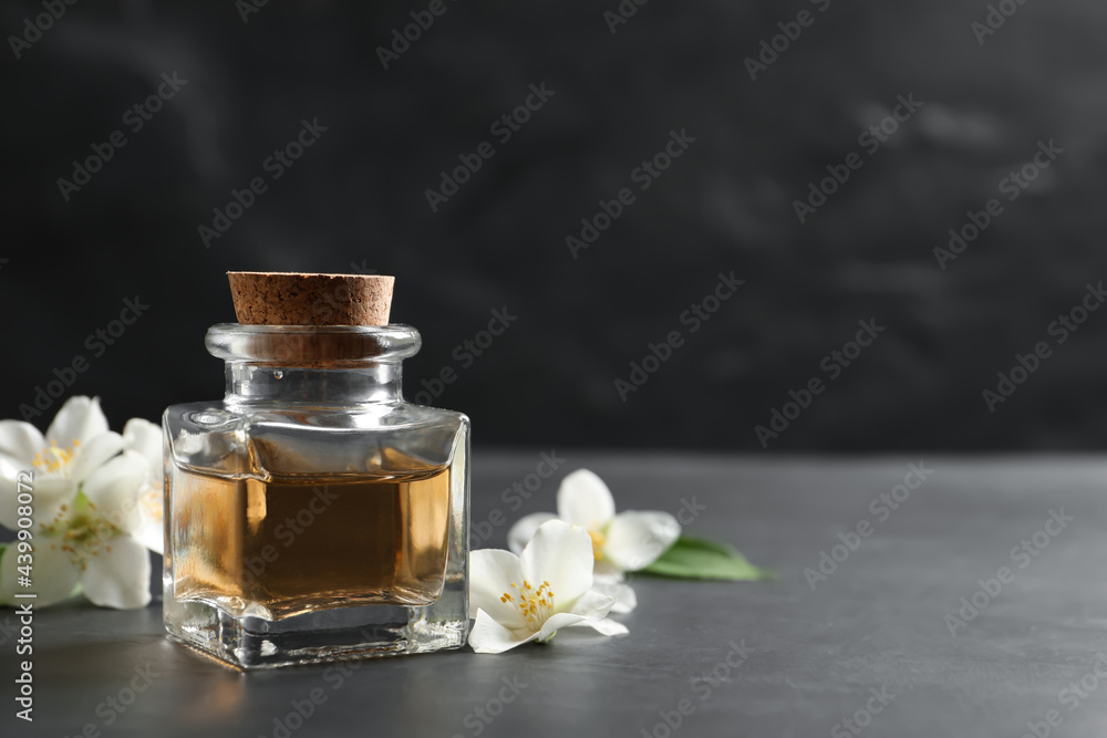 Jasmine essential oil and fresh flowers on dark grey table, space for text Jasmine essential oil and fresh flowers on dark grey table, space for text