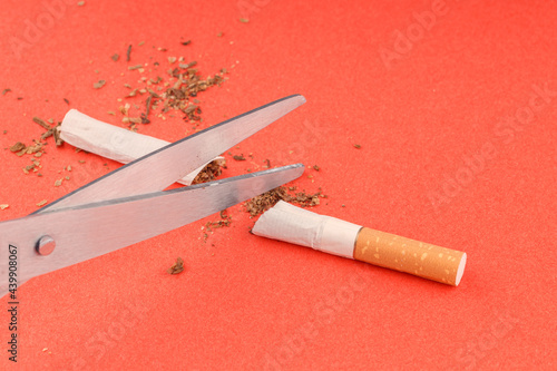 a cigarette cut in half, scissors open in the foreground
