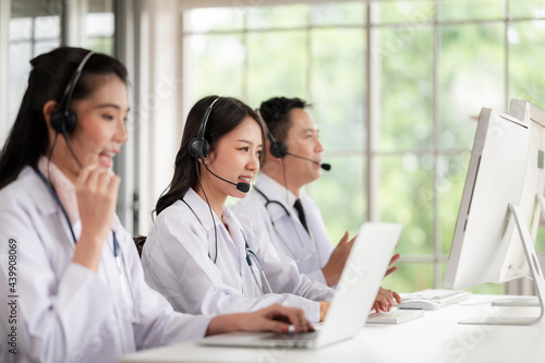 Asia medical service team health advice online. Smiling face stood wearing the headphones with a microphone and stethoscope in clinics.Concept of remote medicine, health care call center online.