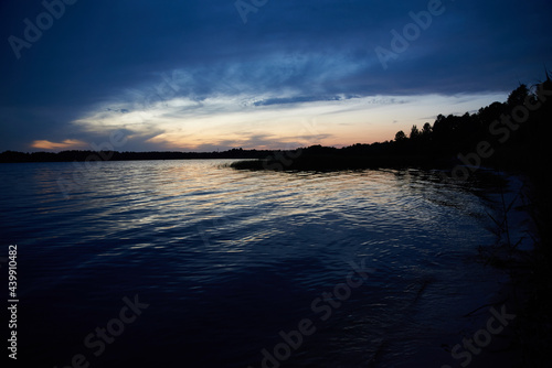 Sunset on the river bank near the forest © dvoinik