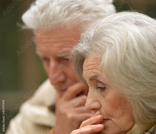 Sad thoughtful senior couple in park
