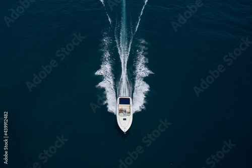 Large boat at high speed on dark blue water and top view. White boat top view. Aerial view of a boat in motion in dark water. © Berg