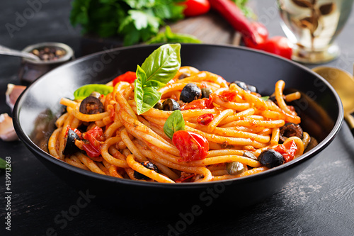Spaghetti alla puttanesca - italian pasta dish with tomatoes, black olives, capers, anchovies and basil.