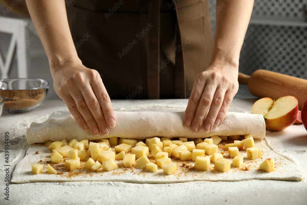 Woman making delicious apple strudel at table, closeup