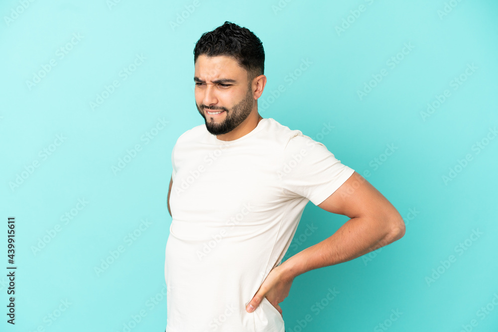 Young arab man isolated on blue background suffering from backache for having made an effort Young arab man isolated on blue background suffering from backache for having made an effort