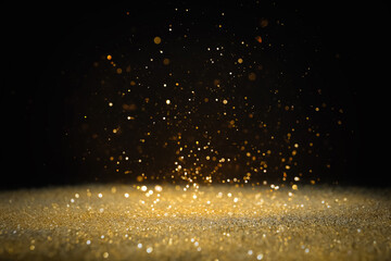 Shiny golden glitter falling down on black background. Bokeh effect