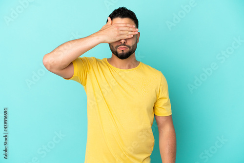 Young arab man isolated on blue background covering eyes by hands. Do not want to see something