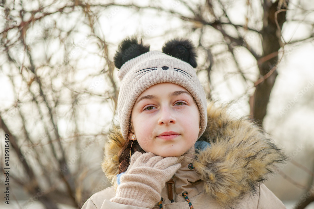Outdoor portrait of adorable 10- 11 year old girl wearing warm jacket. A schoolgirl in a beige hat. Outdoor portrait of adorable 10- 11 year old girl wearing warm jacket. A schoolgirl in a beige hat.