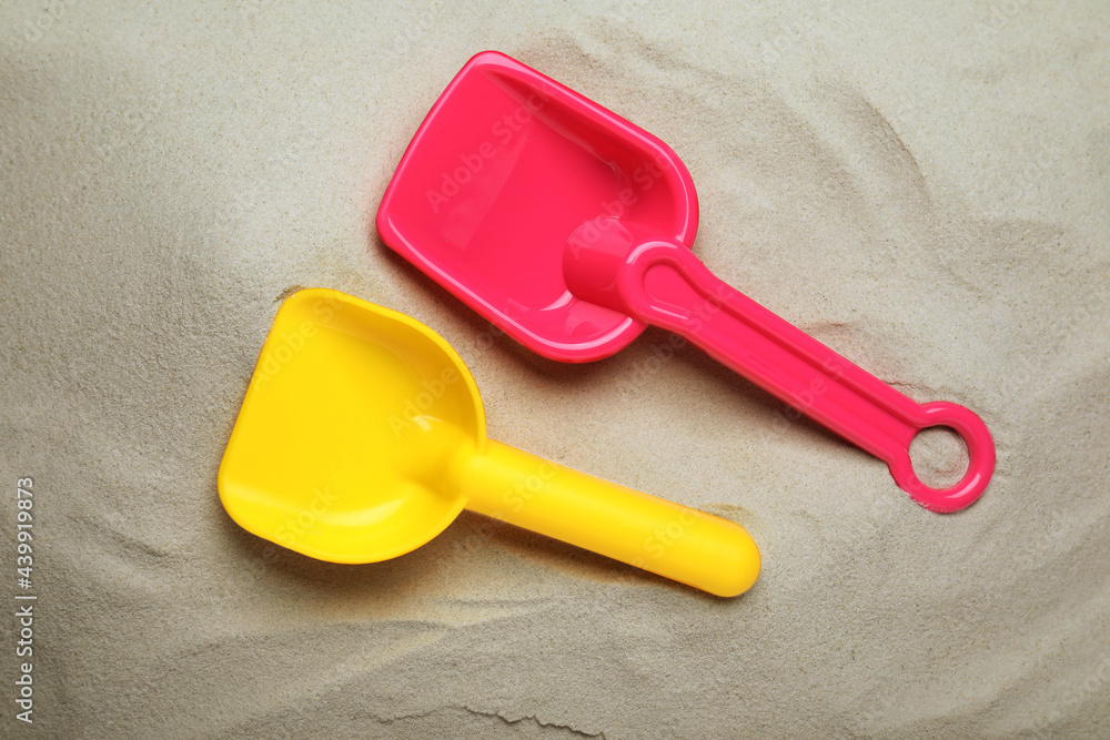 Bright plastic toy shovels on sand, flat lay Bright plastic toy shovels on sand, flat lay