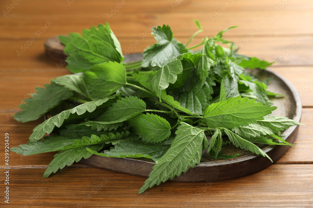 Board with fresh stinging nettle leaves on wooden table, closeup Board with fresh stinging nettle leaves on wooden table, closeup