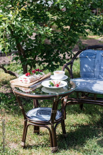 Merengue roll on the table in the garden. Tea drinking in the garden on a summer day. Against the background of green foliage.