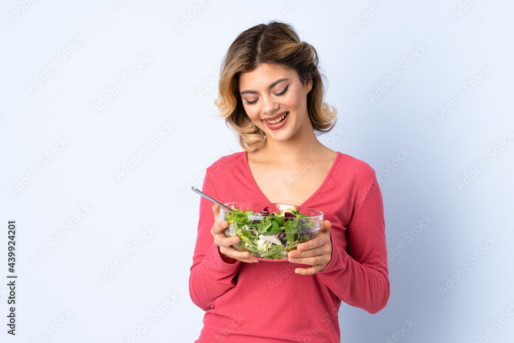 Teenager woman with salad isolated on blue background Teenager woman with salad isolated on blue background