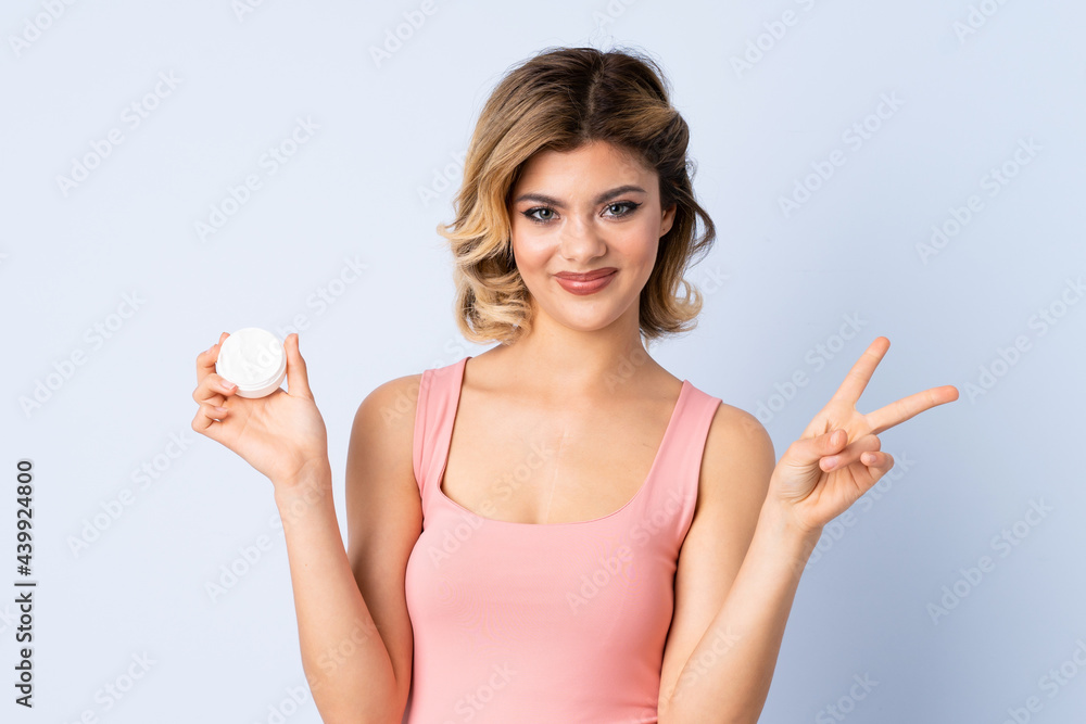 Young girl with moisturizer smiling and showing victory sign Young girl with moisturizer smiling and showing victory sign