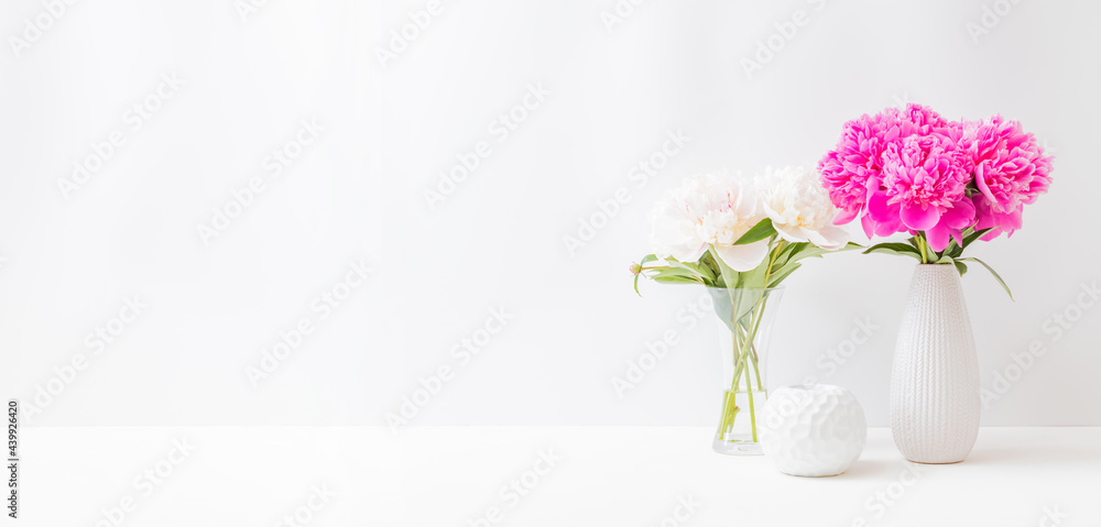 Minimalist home interior with decor elements. Pink peonies in a vase on a light background