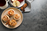 Freshly baked apple roses served on grey table, flat lay. Space for text