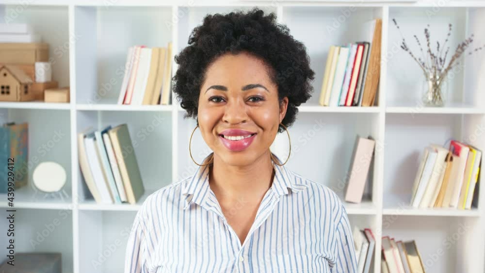 Portrait of African American young business woman in stylish interior. Happy black female student with books on the background. 4K. Portrait of African American young business woman in stylish interior. Happy black female student with books on the background. 4K.