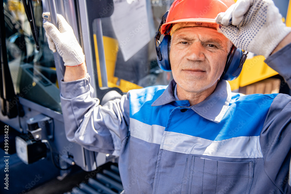 Portrait smile Industrial worker engineer old man in protective helmet and headphones background factory Portrait smile Industrial worker engineer old man in protective helmet and headphones background factory
