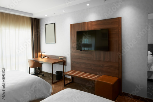 Modern hotel bedroom with a TV and work desk