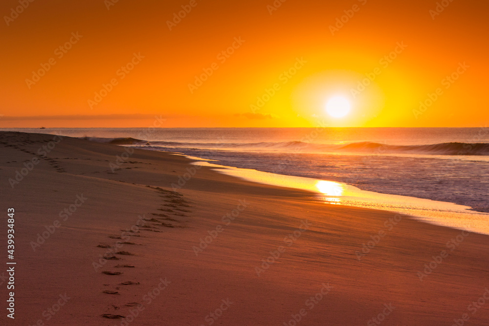 amanecer en la playa con huellas en la arena