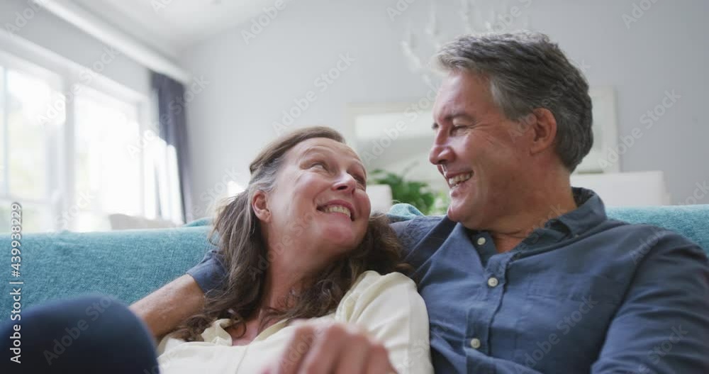 Happy senior caucasian couple sitting in living room watching tv and talking Happy senior caucasian couple sitting in living room watching tv and talking