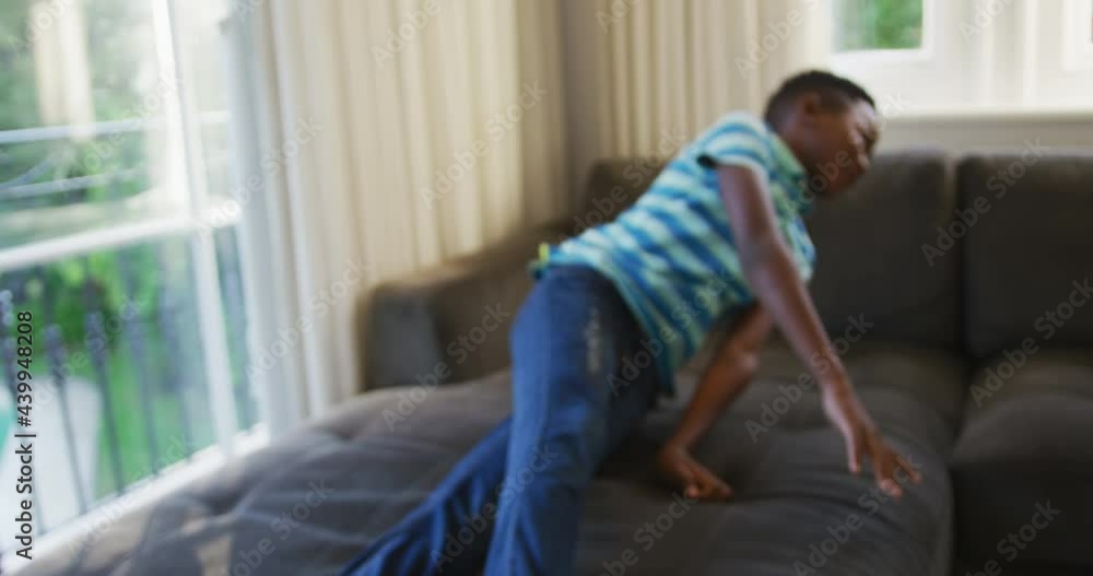 Smiling african american boy jumping on the couch at home Smiling african american boy jumping on the couch at home