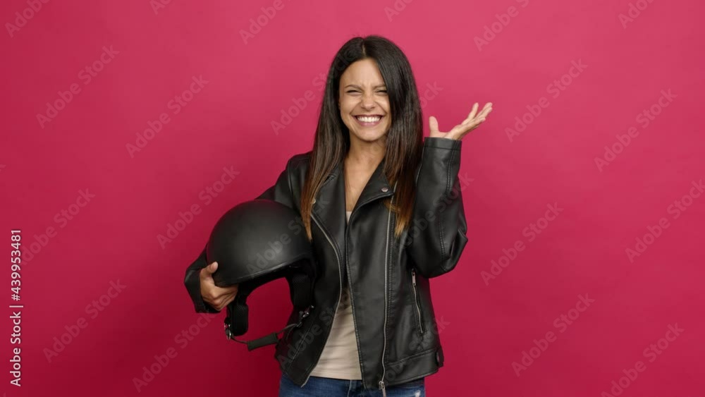Young woman holding a motorcycle helmet with surprise and shocked facial expression over isolated background Young woman holding a motorcycle helmet with surprise and shocked facial expression over isolated background