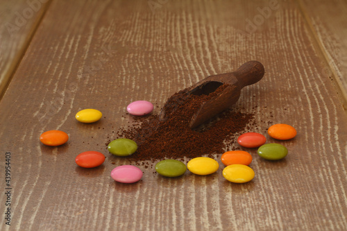 multi-colored candy and roasted coffee beans on brown background. With wooden spoon. delicious and exquisite dessert, close up