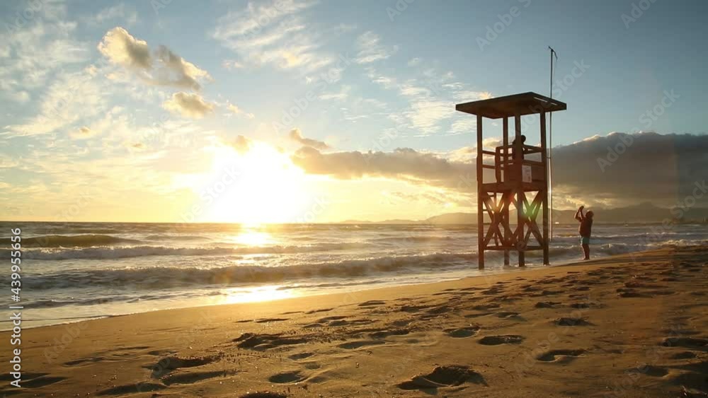 People in the lifeguard tower during gorgeous sunset, colorful sky, tropical People in the lifeguard tower during gorgeous sunset, colorful sky, tropical