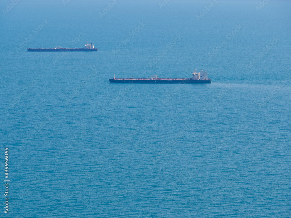 Two empty tankers in the blue sea. Shipping transport goes to the port for loading. Photo side view from the shore.