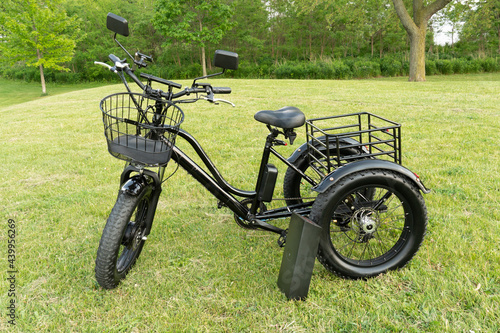 Electric trike or bicycle in the park in sunny summer day. Unfiltered, with natural lighting. E motor and power battery of the three wheel bike. Ecology and green energy concept. Ev – electric vehicle