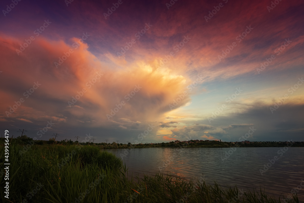 Amazing sunrise by the lake with colorful clouds and vegetation in the foreground