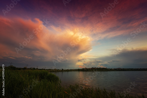 Amazing sunrise by the lake with colorful clouds and vegetation in the foreground