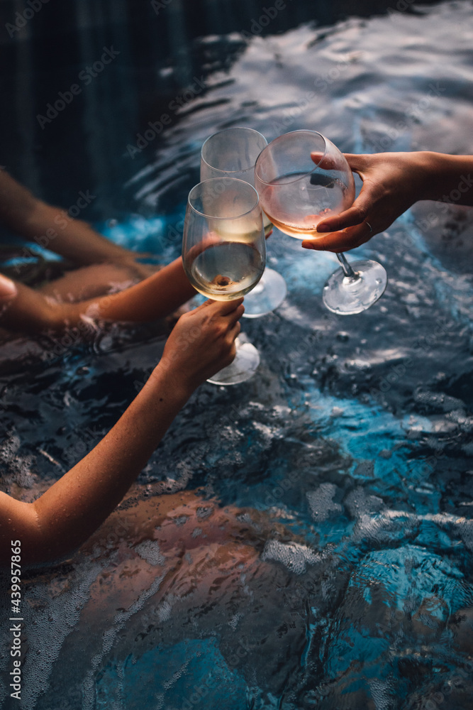 Women with wine glasses in hot tub - obrazy, fototapety, plakaty 