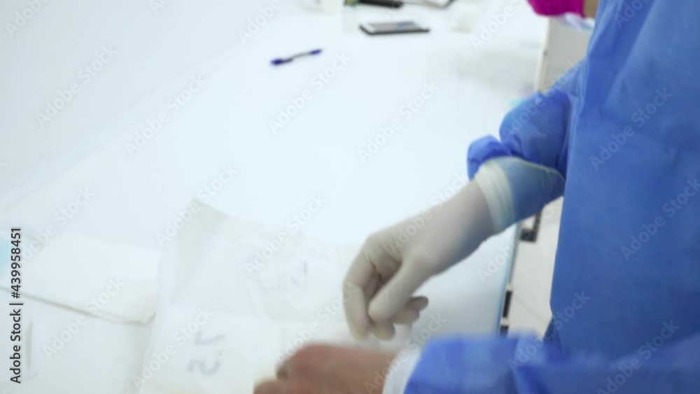 A medical worker standing with a disposable surgical mask, putting on the sterile medical disposable gloves . Protection and safety during pandemic concept in hospital dentistry A medical worker standing with a disposable surgical mask, putting on the sterile medical disposable gloves . Protection and safety during pandemic concept in hospital dentistry