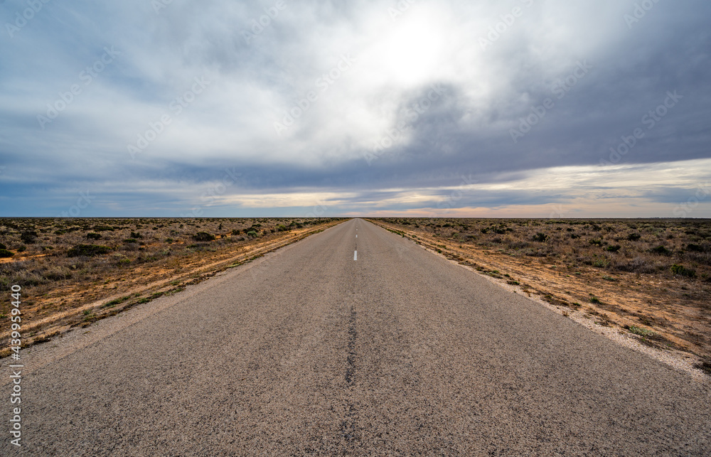 Straight road in flat semi-arid rangeland on Nullarbor Plain in South Australia Straight road in flat semi-arid rangeland on Nullarbor Plain in South Australia