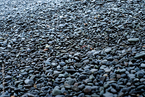 Wet black glistening stones, round shiny pebbles of various minerals, empty full frame space for text.